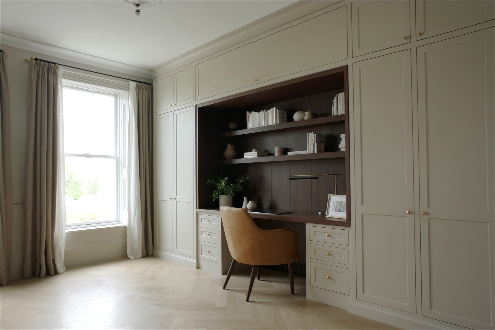 A fitted home office in cream shaker with a walnut-lined desk recess and floating walnut shelves